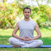 Focused young Indian man meditating in lotus pose